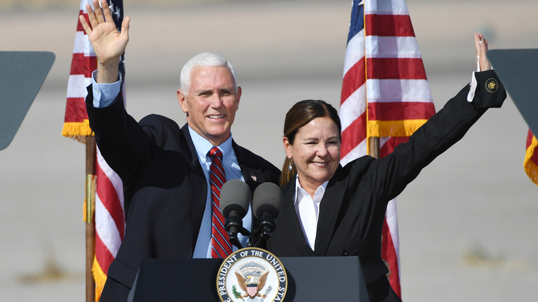 Mike Pence and his wife wave from behind a podium