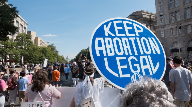 Protestors walk the street in Washington DC while holding a sign that says Keep Abortion Legal
