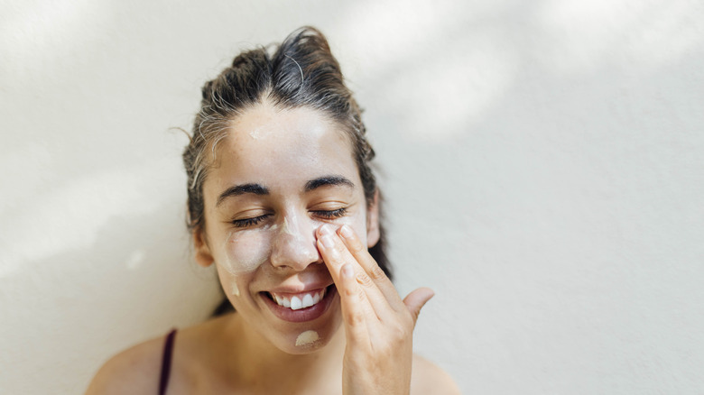 Woman smiling and applying skincare