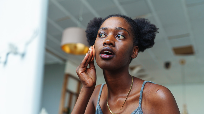 Woman applying skincare in mirror