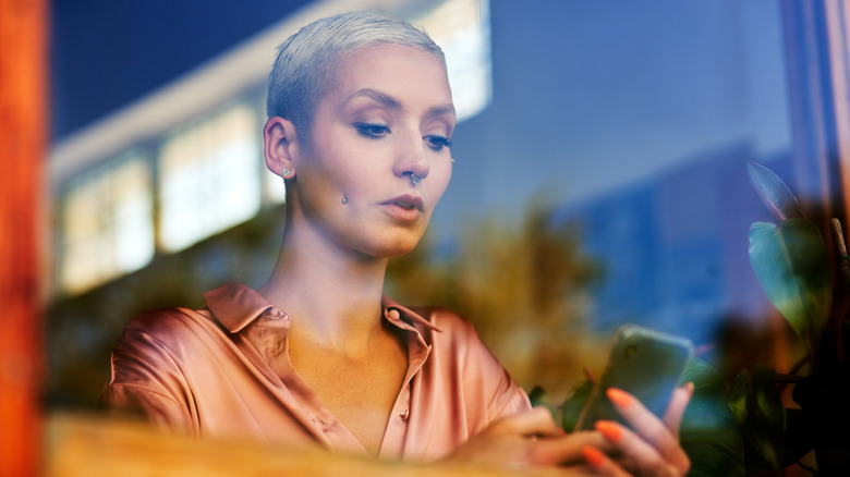 Woman sitting in a window looking at her phone