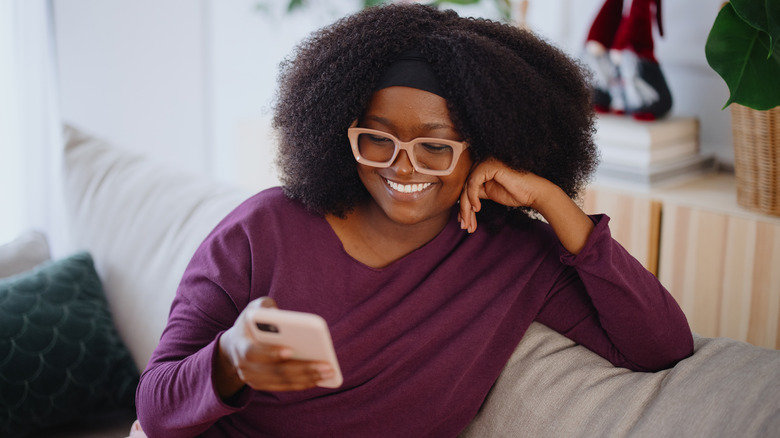 Woman on the sofa holding her phone and smiling