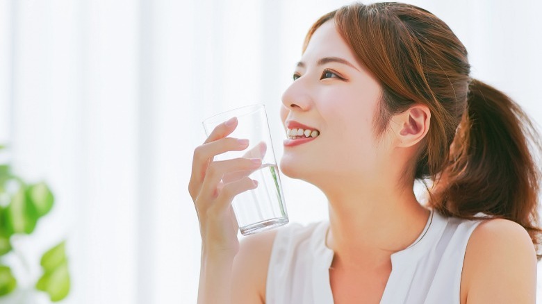 Woman smiles while drinking a glass of water