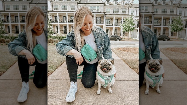 Woman kneeling on the ground outside with pug