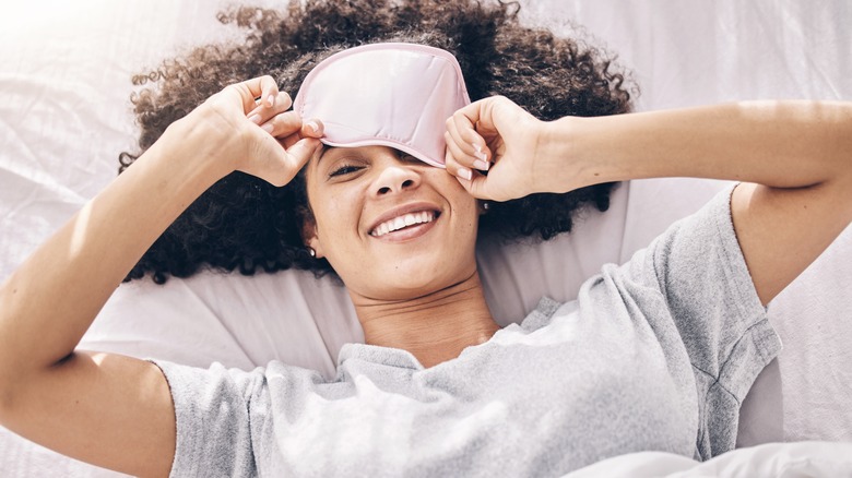 A woman peeking out from under a sleep mask.