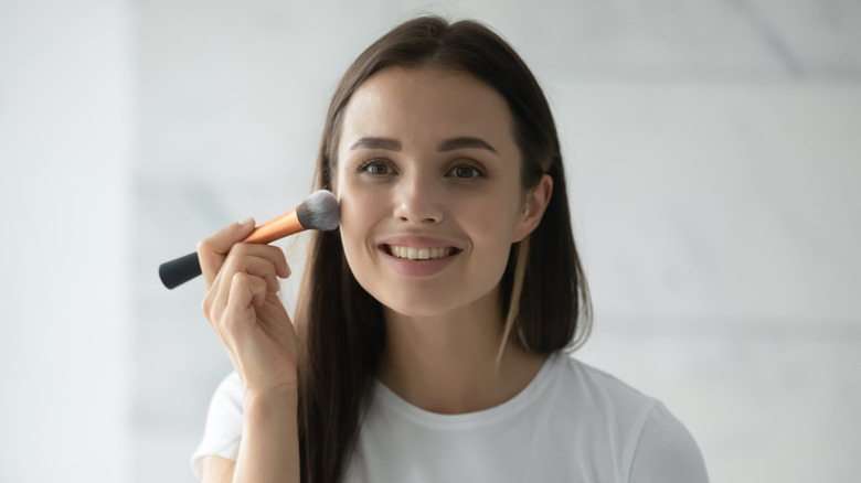 Woman smiling while putting on makeup 