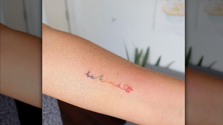 "Be Kind" script tattoo in rainbow lettering