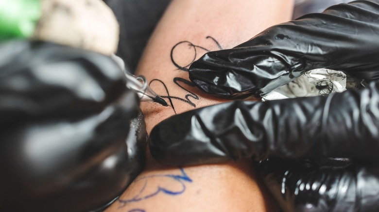 A close-up of an in-process cursive lettering tattoo