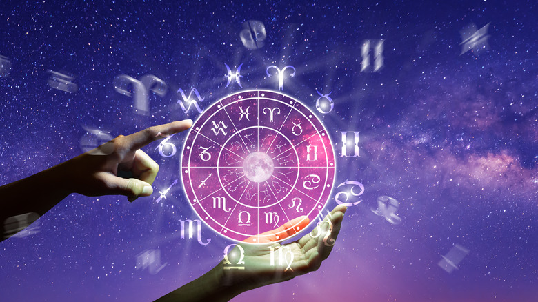 Hands pointing to astrological signs at night