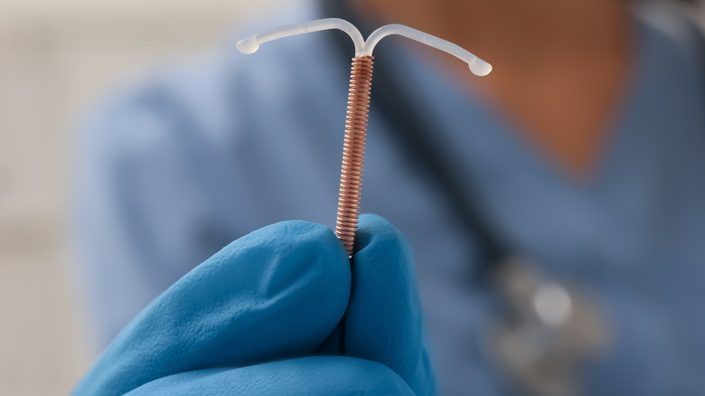 Blue-gloved hand holding copper IUD